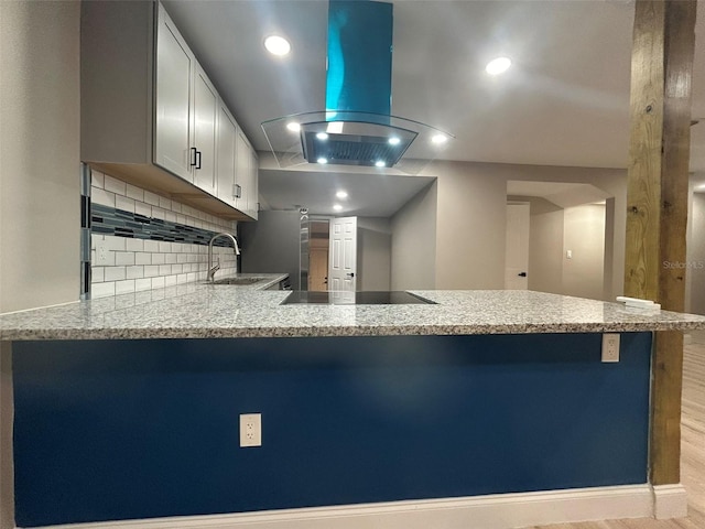 kitchen with island exhaust hood, black electric stovetop, white cabinetry, a sink, and a peninsula