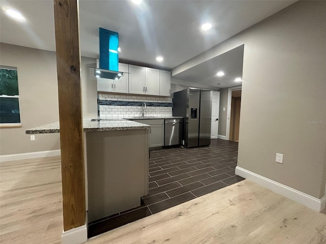 kitchen with light stone counters, white cabinetry, appliances with stainless steel finishes, backsplash, and dark wood finished floors