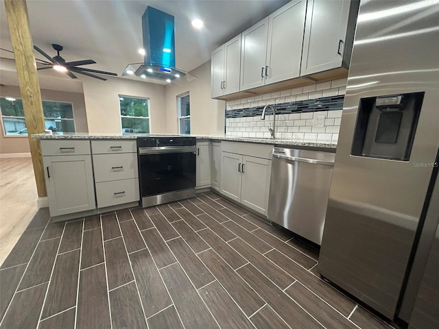 kitchen featuring appliances with stainless steel finishes, wood tiled floor, white cabinetry, and island exhaust hood