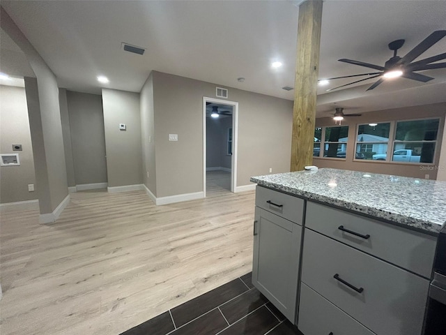 kitchen featuring light wood-style floors, visible vents, gray cabinetry, and light stone countertops