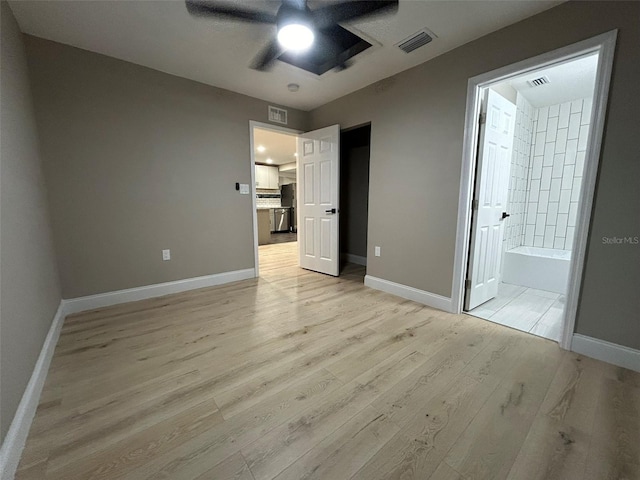 unfurnished bedroom with ensuite bath, light wood-style flooring, visible vents, and baseboards