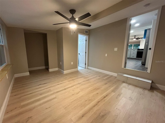 spare room featuring a ceiling fan, visible vents, light wood-style flooring, and baseboards