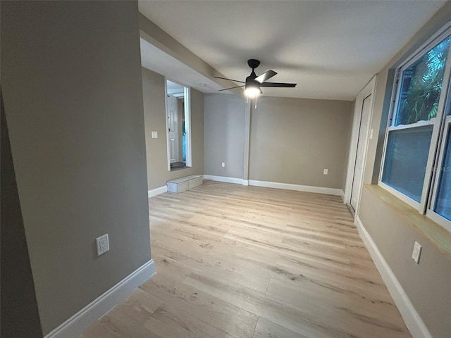 empty room featuring light wood finished floors, a ceiling fan, and baseboards