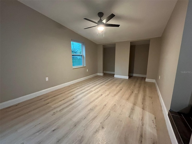 unfurnished bedroom featuring light wood-style floors, lofted ceiling, ceiling fan, and baseboards