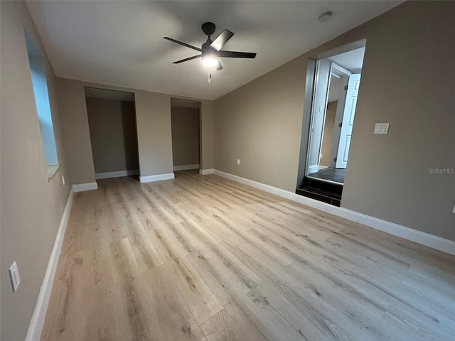 unfurnished bedroom with lofted ceiling, light wood-type flooring, a ceiling fan, and baseboards