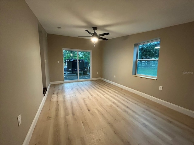 spare room featuring light wood-style floors, ceiling fan, and baseboards