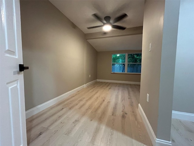 spare room with ceiling fan, light wood-type flooring, lofted ceiling, and baseboards