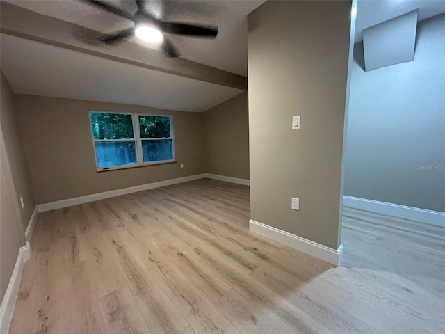 additional living space featuring lofted ceiling with beams, light wood-type flooring, a ceiling fan, and baseboards