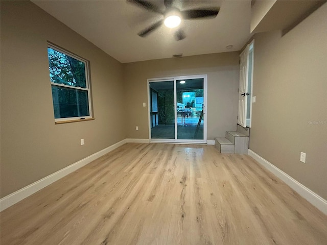 spare room with ceiling fan, light wood finished floors, visible vents, and baseboards