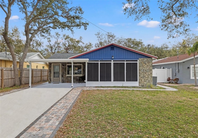 back of house featuring stone siding, a sunroom, a yard, and fence