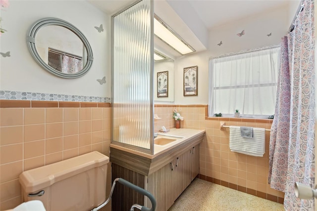 4310 Indian Lake Dr, Indian Lake Estates, FL 33855 - full bathroom featuring toilet, speckled floor, vanity, tile walls, and wainscoting
