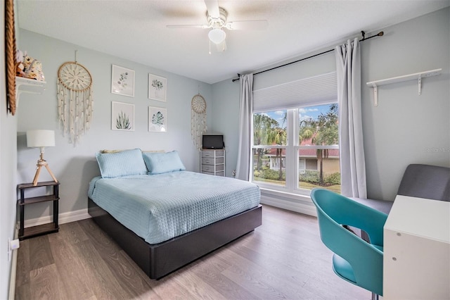 bedroom with ceiling fan, baseboards, and wood finished floors