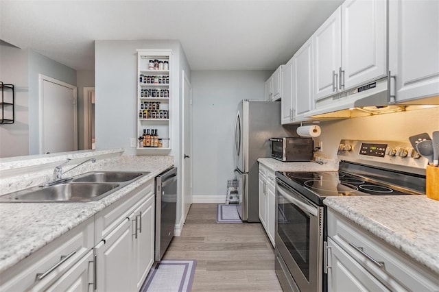 kitchen featuring white cabinets, stainless steel appliances, light countertops, under cabinet range hood, and a sink