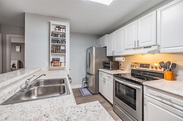 kitchen with under cabinet range hood, white cabinetry, appliances with stainless steel finishes, and a sink