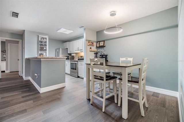 dining space featuring baseboards, visible vents, and wood finished floors