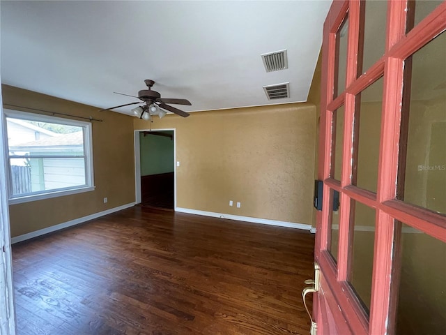 empty room with baseboards, ceiling fan, visible vents, and dark wood-style flooring