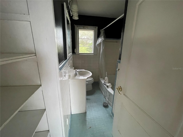 bathroom with toilet, vanity, washtub / shower combination, and tile walls