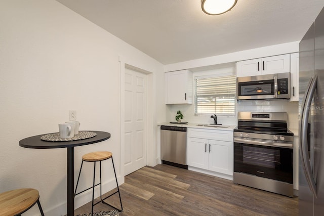 kitchen with decorative backsplash, appliances with stainless steel finishes, white cabinets, and dark wood finished floors