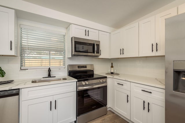 kitchen featuring appliances with stainless steel finishes, white cabinetry, a sink, and backsplash