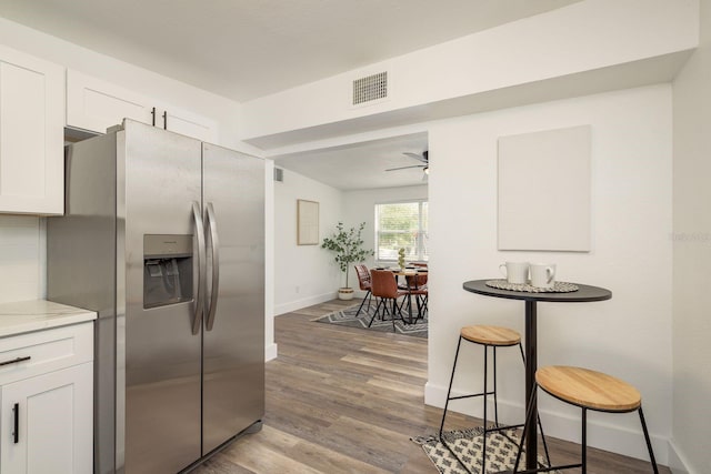 kitchen with a ceiling fan, visible vents, white cabinets, light wood-type flooring, and stainless steel refrigerator with ice dispenser