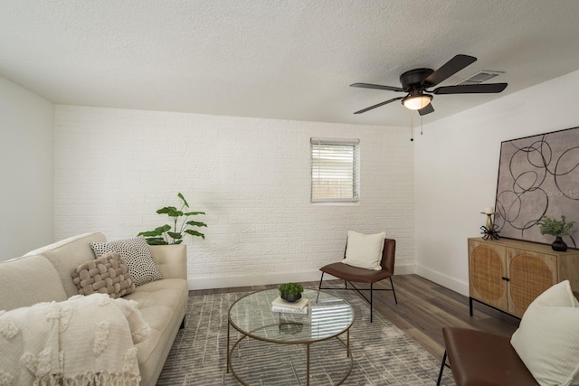 sitting room with a textured ceiling, wood finished floors, visible vents, and baseboards