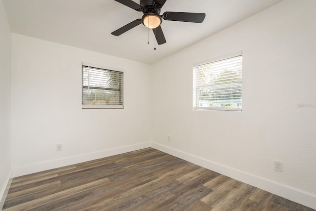 spare room featuring dark wood finished floors, plenty of natural light, and baseboards