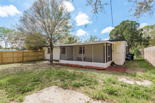 back of house with a sunroom, a fenced backyard, and a lawn