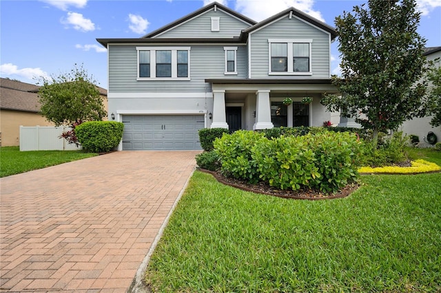 traditional-style home with decorative driveway, an attached garage, a front lawn, and stucco siding