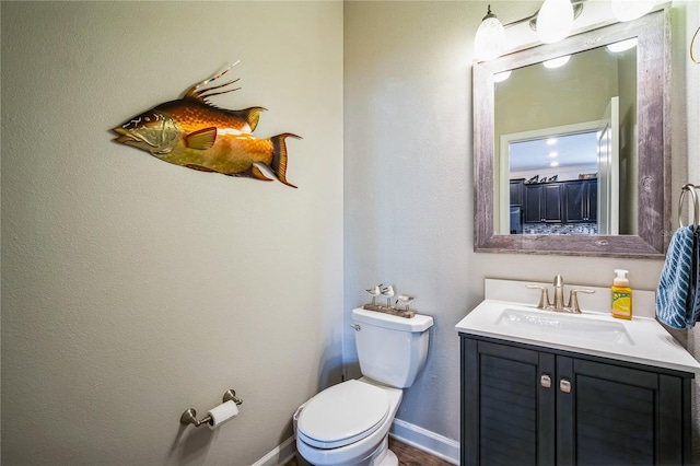 bathroom with toilet, baseboards, and vanity