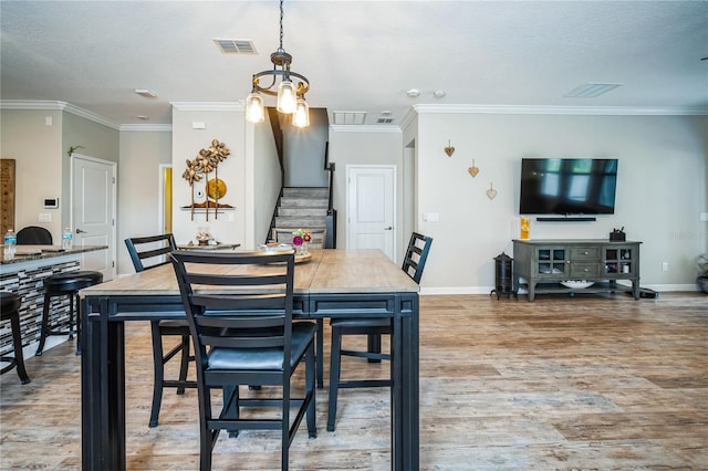 dining space featuring wood finished floors, visible vents, baseboards, stairs, and ornamental molding