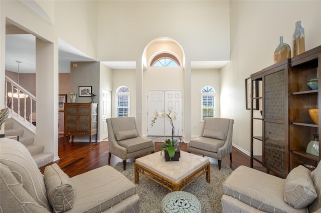 living room with a high ceiling, stairway, wood finished floors, and baseboards