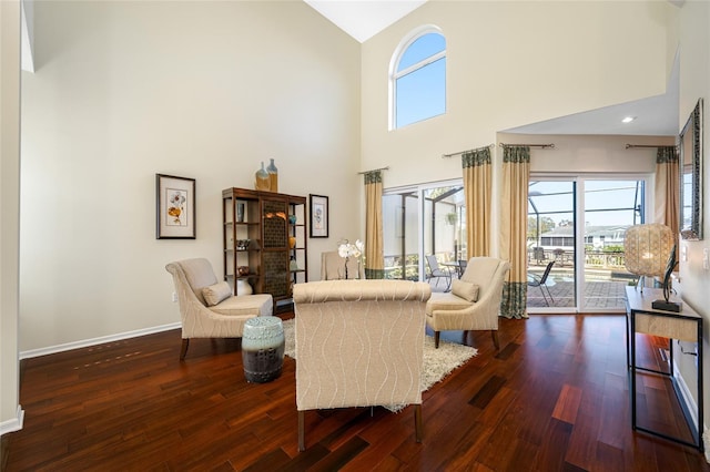 sitting room featuring a towering ceiling, baseboards, and wood finished floors