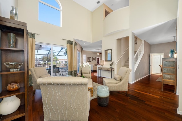 living area featuring stairs, ceiling fan, wood-type flooring, and baseboards