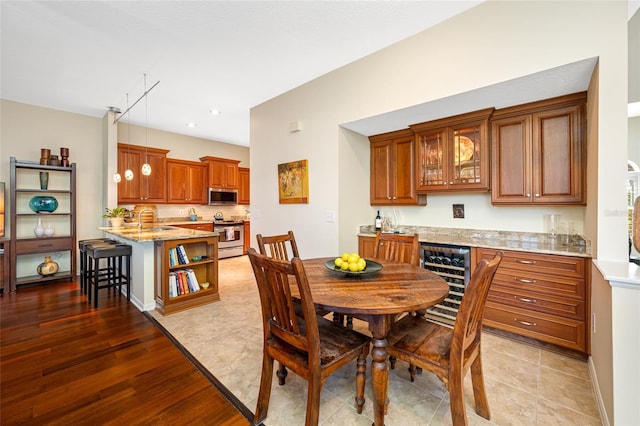 dining area featuring light wood finished floors, beverage cooler, and baseboards