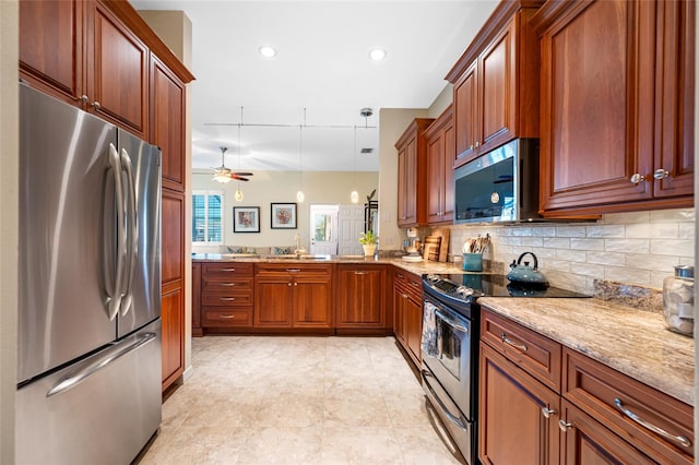 kitchen with stainless steel appliances, a peninsula, a sink, light stone countertops, and tasteful backsplash