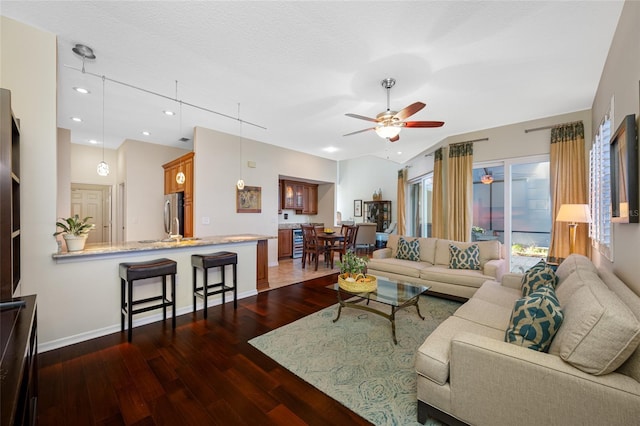 living room with ceiling fan, a textured ceiling, baseboards, vaulted ceiling, and dark wood finished floors