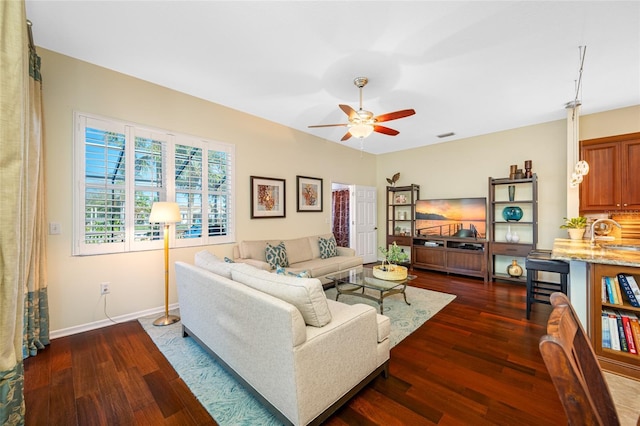 living room featuring ceiling fan, baseboards, and dark wood finished floors