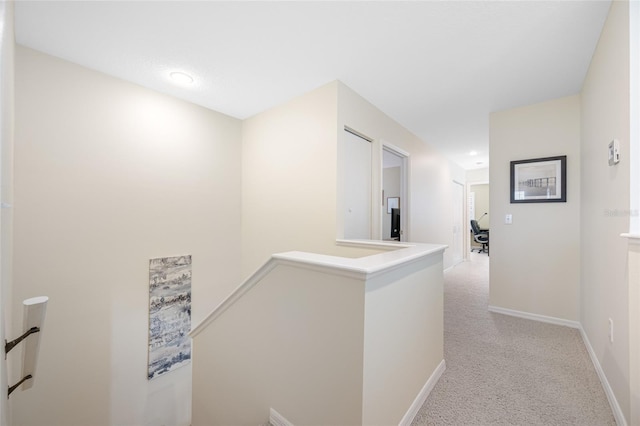 corridor with baseboards, light colored carpet, and an upstairs landing