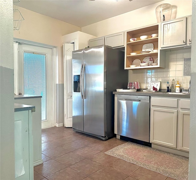 kitchen featuring tile patterned flooring, a sink, appliances with stainless steel finishes, decorative backsplash, and open shelves