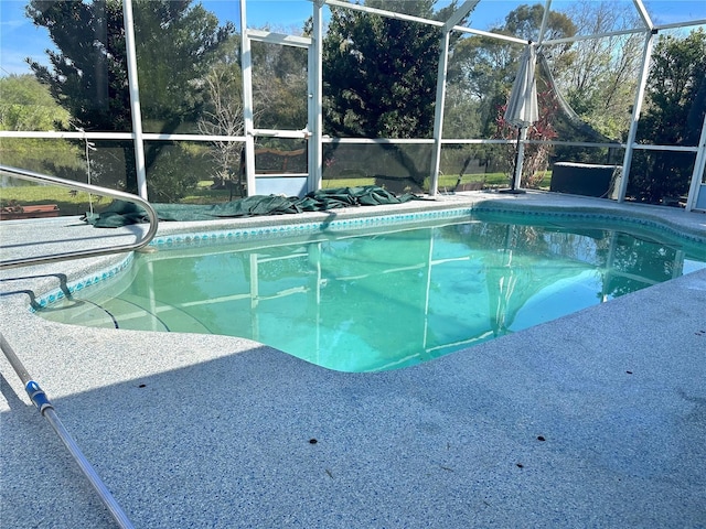 pool with glass enclosure and a patio