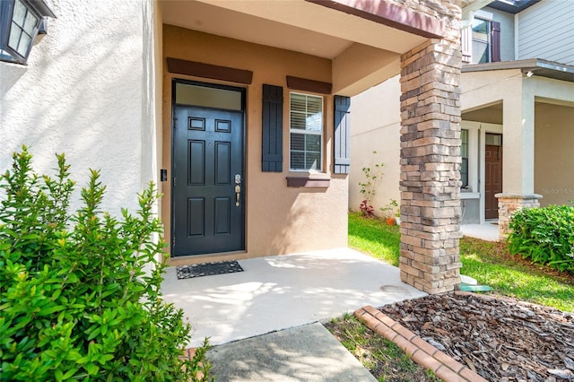 property entrance with covered porch and stucco siding