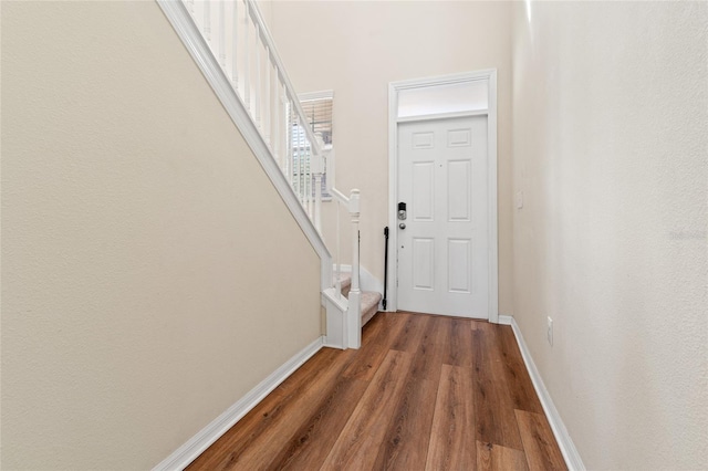 doorway to outside featuring dark wood-style floors, baseboards, and stairs