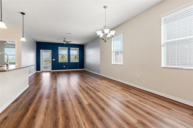 interior space featuring dark wood finished floors, visible vents, a sink, baseboards, and ceiling fan with notable chandelier