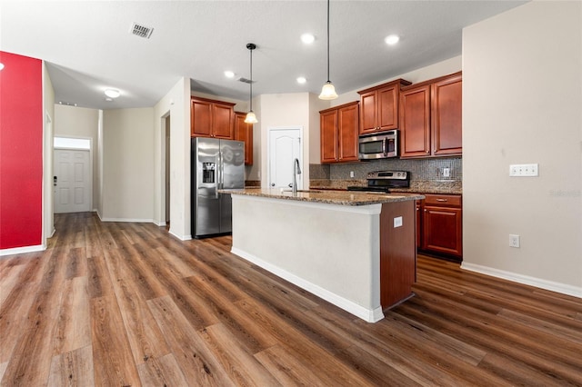 kitchen with a sink, appliances with stainless steel finishes, tasteful backsplash, a center island with sink, and pendant lighting