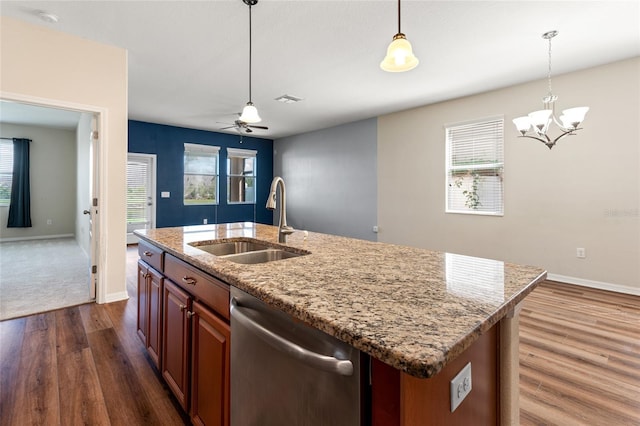 kitchen featuring dark wood-style flooring, a sink, hanging light fixtures, dishwasher, and an island with sink