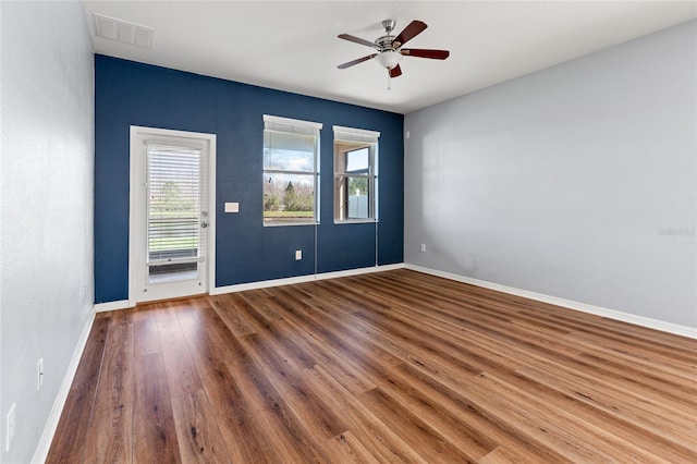 unfurnished room with a ceiling fan, baseboards, visible vents, and wood finished floors