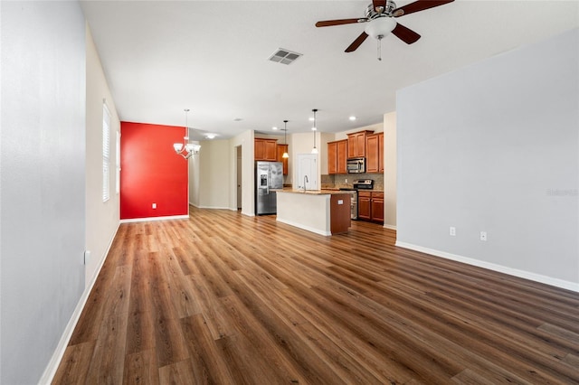 unfurnished living room with dark wood-style flooring, visible vents, baseboards, and ceiling fan with notable chandelier