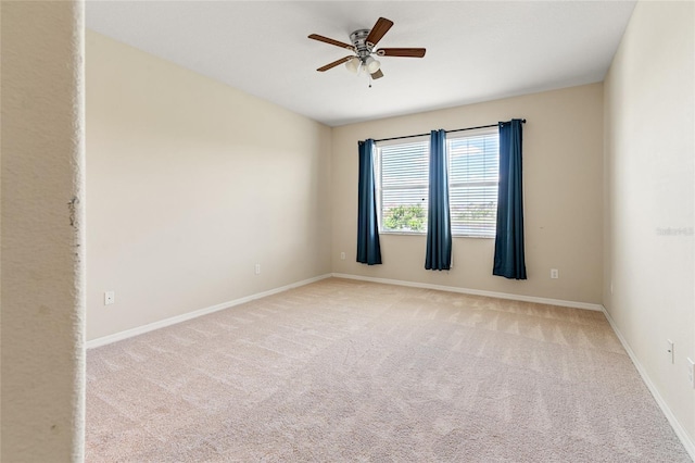 empty room with light carpet, a ceiling fan, and baseboards