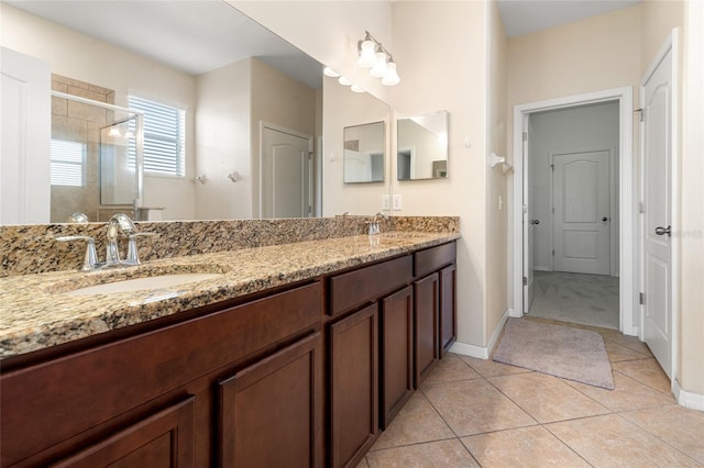 full bath featuring double vanity, a stall shower, tile patterned flooring, and a sink