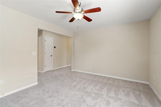 spare room with light carpet, ceiling fan, and baseboards